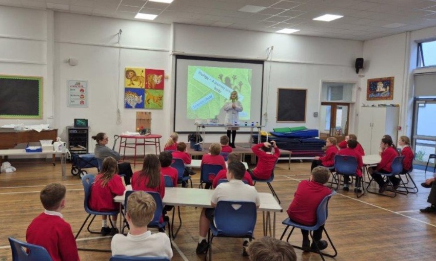 Science teacher standing in front of a projected slide titled “Biology – A Journey Around Our Body” while delivering the science show.